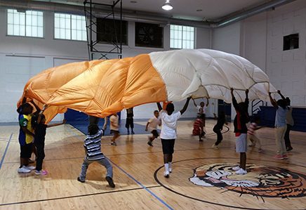 kids playing with parachute in gym