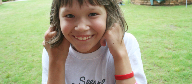 special needs camper smiling and holding her ears