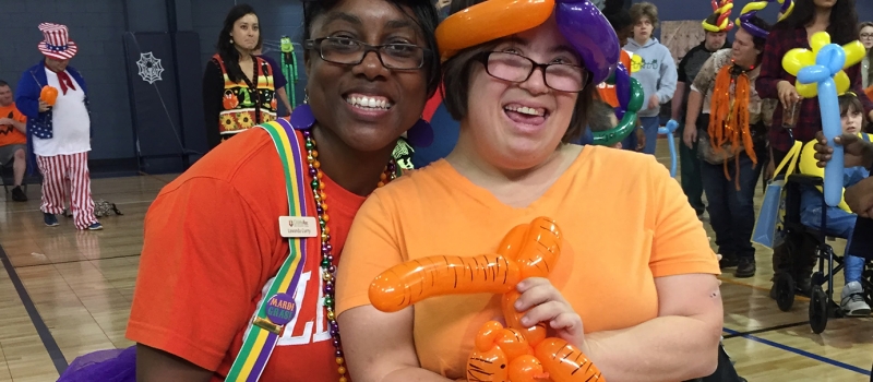volunteer and camper dressed in mardi gras costumes